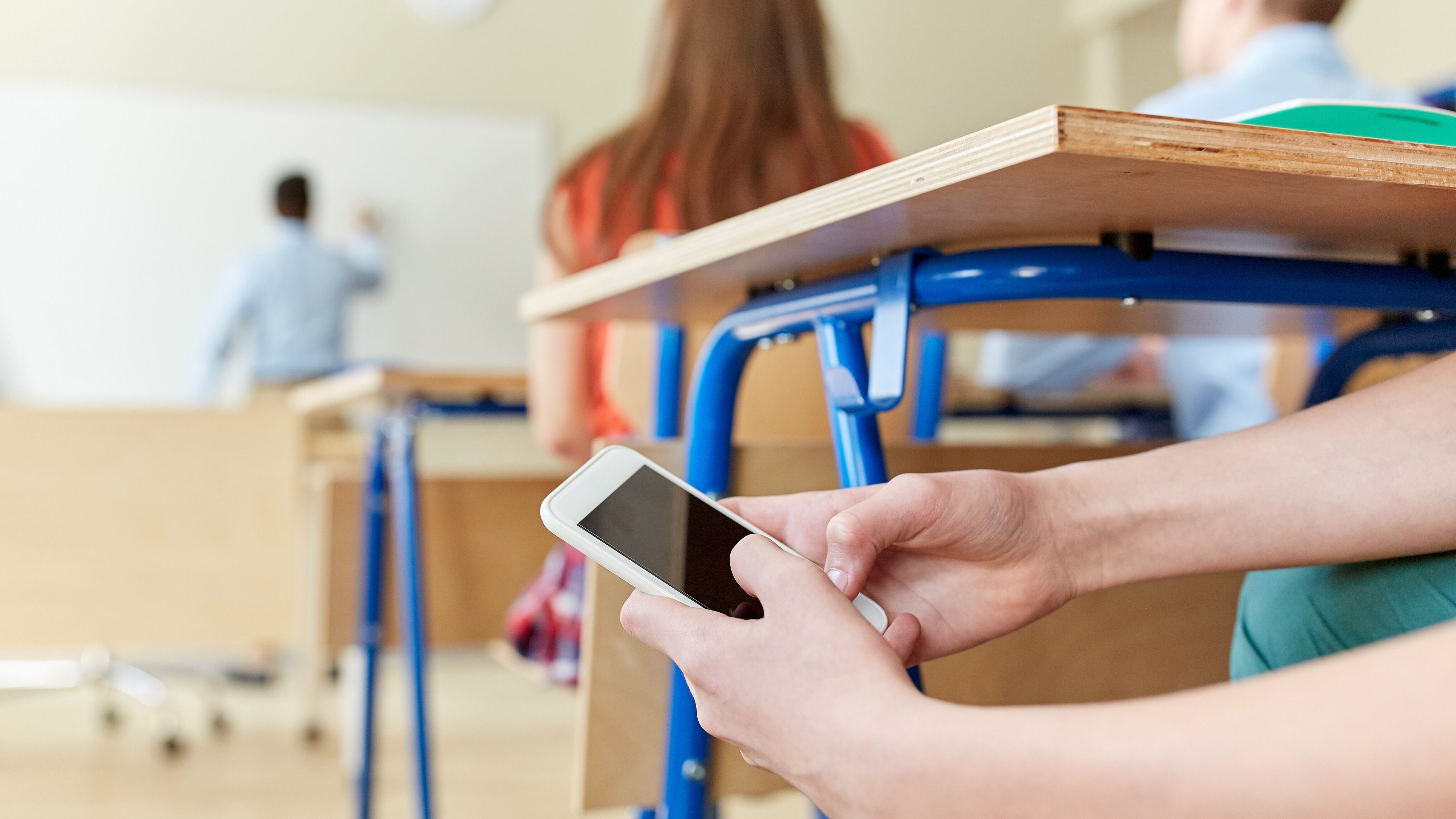 education, high school, learning, technology and people concept - student boy hands with smartphone texting on lesson