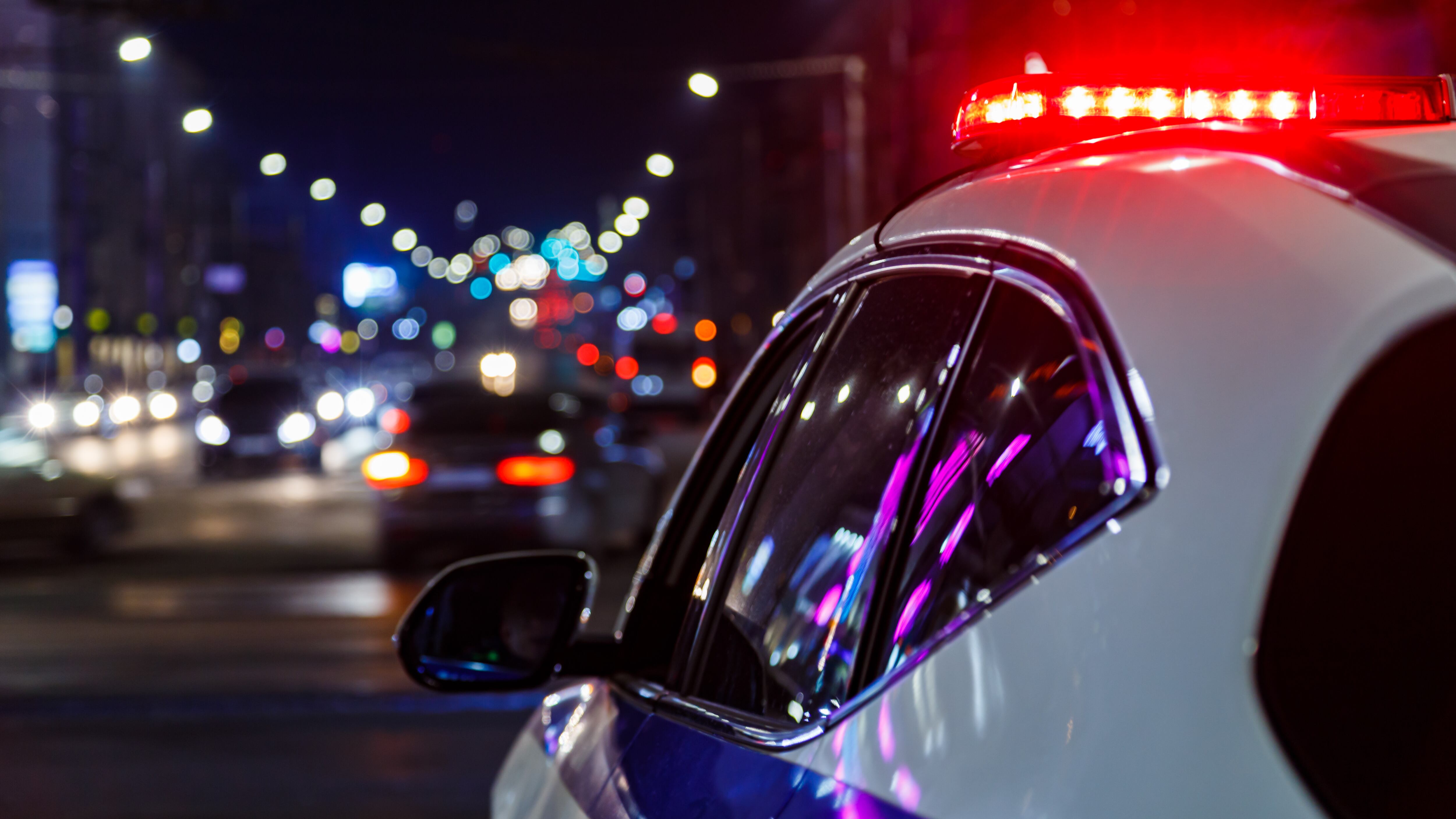 police car lights at night in city with selective focus and blurry car traffic