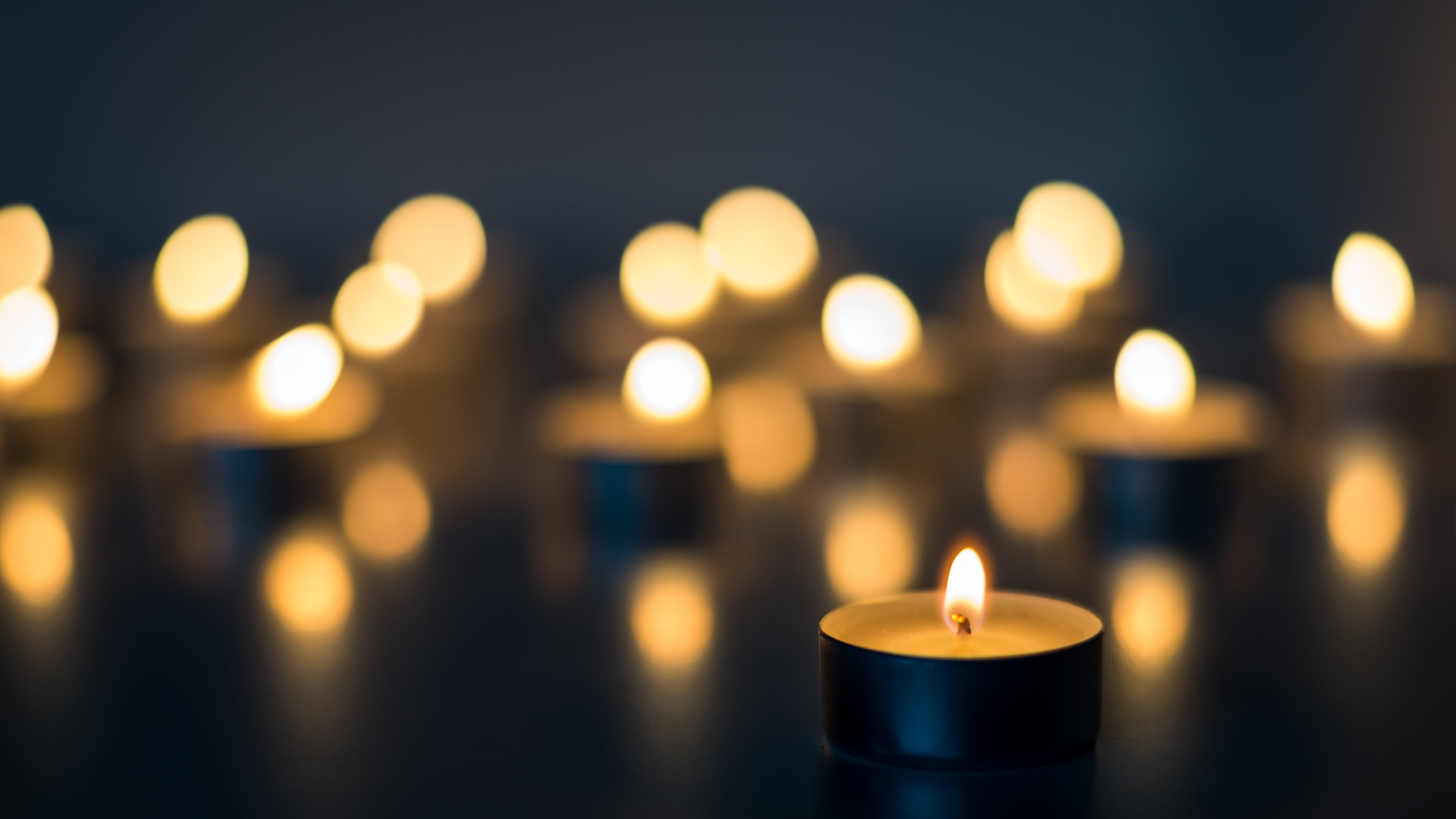 Flame of many candles burning on the background in blue and yellow color
