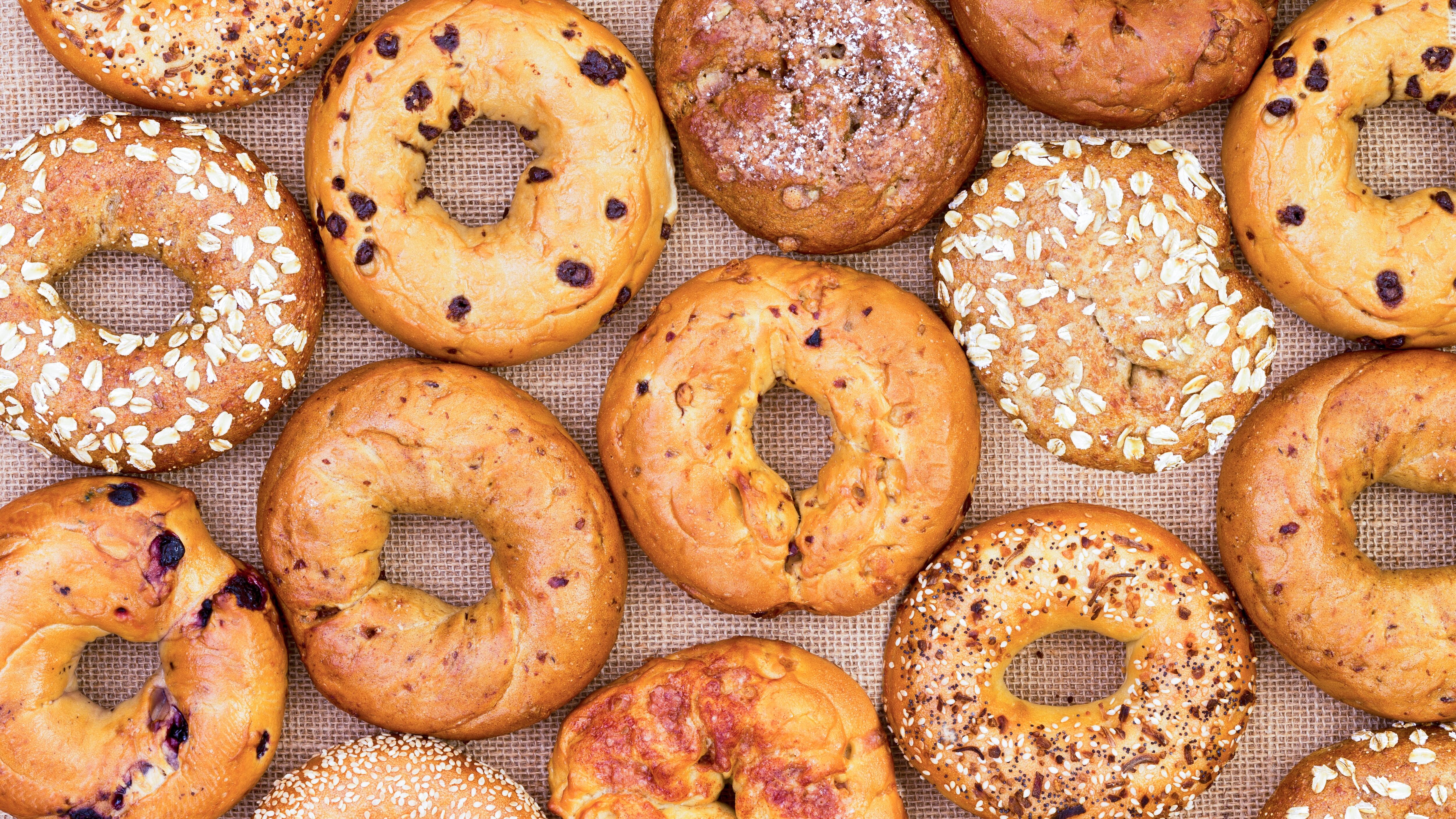 Assorted variety of different flavored freshly baked bagels in a full frame background on burlap viewed from above in an abstract pattern