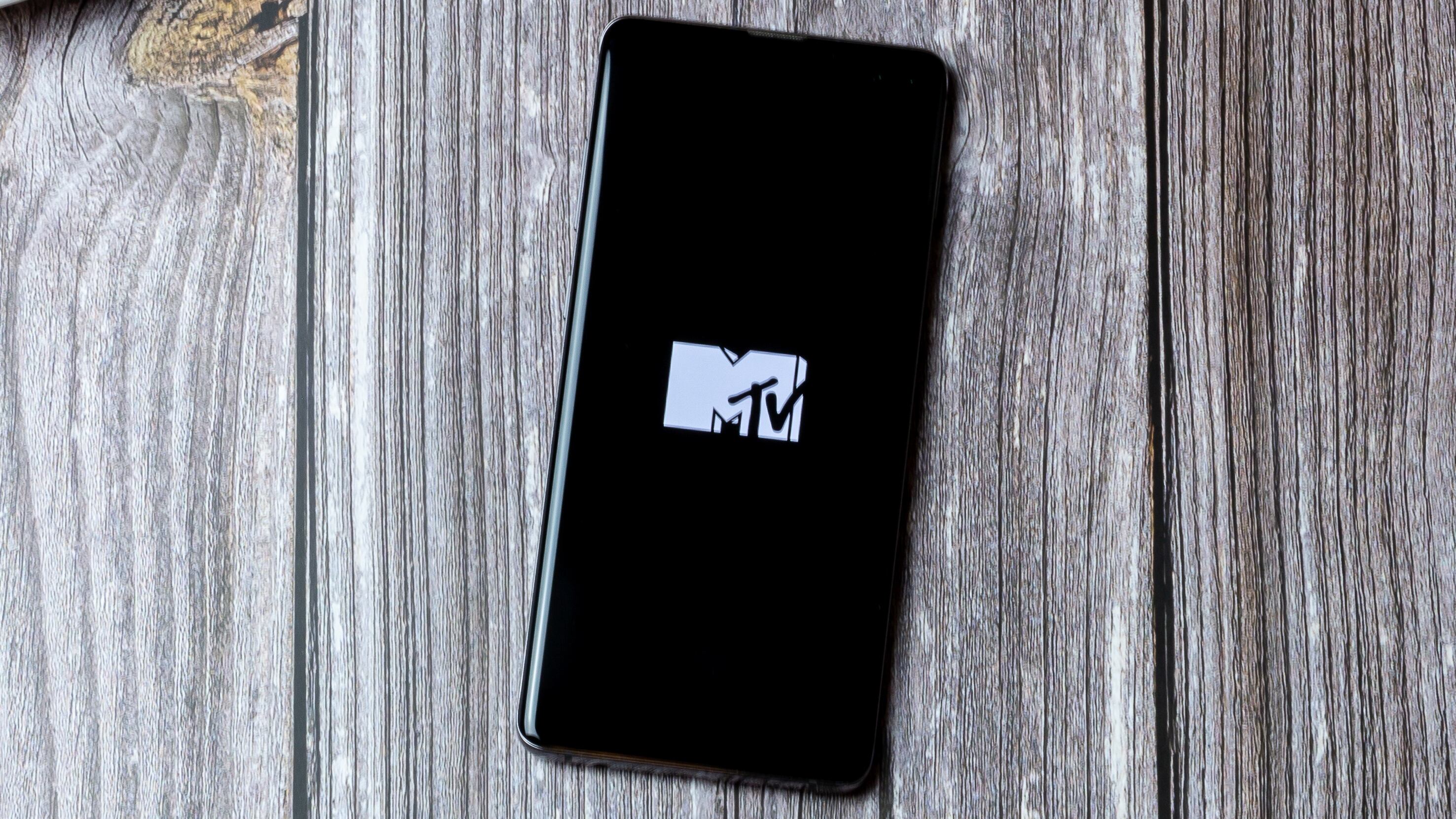 Portsmouth, Hampshire, UK A mobile phone or cell phone is on a wooden table with the MTV app open on screen