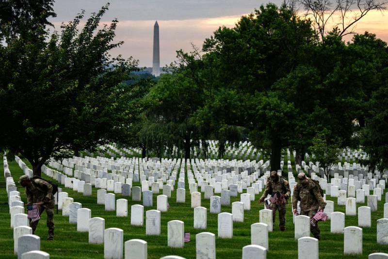 ARLINGTON, VIRGINIA - MAY 23: Members of the 3rd U.S. Infantry Regiment, also known as the "Old Guard," place flags at the headstones of U.S. military personnel buried at Arlington National Cemetery ahead of Memorial Day, on May 23, 2024 in Arlington, Virginia. Nearly 1,500 joint service members will spend around four hours placing small American flags in front of more than 260,000 headstones. The cemetery, consisting of 639 acres, is the final resting place of approximately 400,000 veterans and their dependents. (Photo by Kent Nishimura/Getty Images)